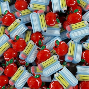 May include: A collection of colorful, flatback resin cabochons featuring a stack of books and a pencil, and a red apple. These are great for crafting and scrapbooking.