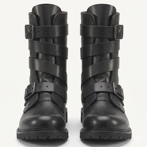 May include: A pair of black mid-calf boots featuring a smooth leather construction, rounded toes, and thick lug soles. Each boot is secured with three horizontal straps across the front, each finished with a dark metal buckle and matching hardware.