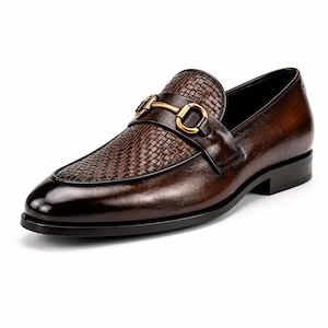 Pode incluir: Um mocassim de couro castanho escuro com uma textura entran&ccedil;ada no peito do p&eacute; e um detalhe de brid&atilde;o em metal dourado polido no topo. O sapato tem um acabamento polido suave, biqueira arredondada e um salto baixo preto com sola preta.