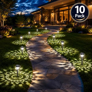 May include: A 10-pack of black solar-powered garden path lights with clear textured lenses. Each light is staked into the grass along a stone walkway, casting a bright, circular, mandala-like pattern of light onto the ground at night.