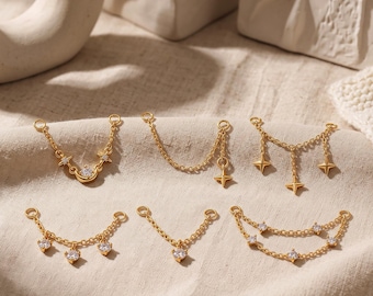 May include: Six gold-toned metal jewelry connector chains featuring various designs, including a crescent moon, four-pointed stars, and clear round cubic zirconia stones. Each piece has small circular loops at both ends for attachment.