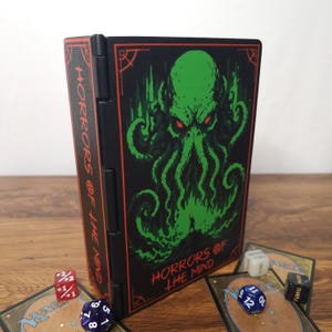 May include: A black rectangular deck box featuring a green tentacled creature illustration and red text reading HORRORS OF THE MIND. The box is surrounded by several multi-sided gaming dice and trading cards on a wooden surface.