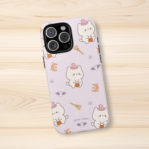 Puede incluir: Una funda de teléfono de color morado claro con un patrón repetitivo de gatos blancos de dibujos animados con sombreros de bruja rosas y calabazas naranjas, junto con escobas amarillas, lunas crecientes naranjas, murciélagos y el texto divine dawn.
