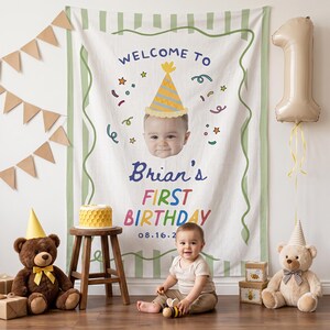 Könnte beinhalten: Ein weißes Stoff-Geburtstagsbanner mit grünem Streifenrand, einer zentralen Illustration eines Babys mit Partyhut und dem Text "WELCOME TO Brian's FIRST BIRTHDAY 08.16.2". Das Banner ist mit buntem Konfetti und Sternen verziert.