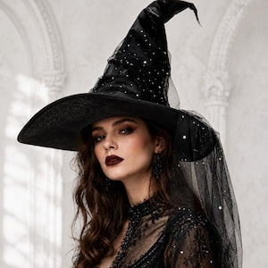 May include: A black pointed hat featuring a wide brim and a tall, structured crown. The hat is adorned with a sheer black tulle overlay embellished with small, reflective silver star patterns and a long, flowing veil of matching black tulle.