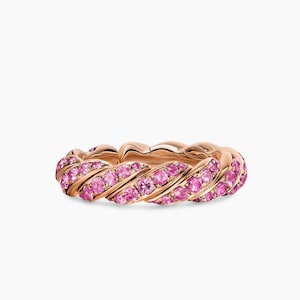 Könnte beinhalten: Ein Ring aus Roségold mit einem gedrehten, seilartigen Banddesign. Die Oberfläche des Rings ist mit zahlreichen kleinen, runden, leuchtend pinkfarbenen Edelsteinen besetzt, die dem Spiralmuster entlang des gesamten Metallbandes folgen.