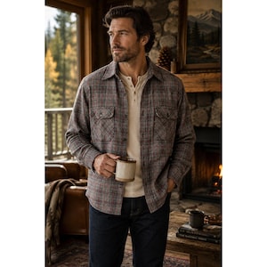 May include: A long-sleeve button-down shirt featuring a brown, grey, and red plaid pattern with two chest pockets, worn over a cream-colored henley shirt paired with dark blue denim jeans. The shirt has a classic collar and buttoned cuffs.