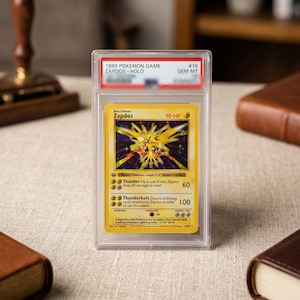 May include: A 1999 Pokemon Game Zapdos holographic trading card encased in a clear protective plastic slab. The card features the yellow electric-type Pokemon with 90 HP, Thunder and Thunderbolt attacks, and a label at the top reading 1999 POKEMON GAME.