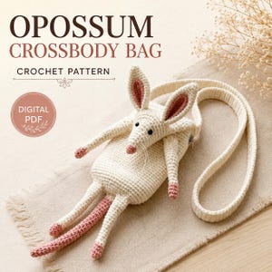 Può includere: Una borsa a tracolla all'uncinetto color bianco sporco a forma di opossum con interno delle orecchie, naso, zampe e coda rosa. La borsa presenta una lunga tracolla, una chiusura a zip e occhi a perla neri. Testo: OPOSSUM CROSSBODY BAG CROCHET PATTERN DIGITAL PDF.