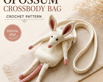 Peut inclure: Un sac bandoulière en crochet blanc cassé en forme d'opossum avec des détails roses sur les oreilles, le nez, les pattes et la queue. Le sac possède une longue bandoulière, une fermeture éclair et des yeux en perles noires. Texte : OPOSSUM CROSSBODY BAG CROCHET PATTERN DIGITAL PDF.