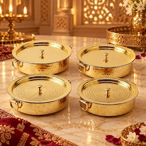 May include: A set of four round, gold-coloured metal containers with matching lids. Each container features a hammered texture on the sides, a circular patterned top, and two small side handles. The lids are topped with a small, central knob.