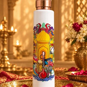 May include: A white cylindrical water bottle with a metallic copper-coloured cap. The bottle features a colourful graphic print depicting a yellow domed building, a sitar, a drum, and an elephant, all rendered in vibrant, multi-coloured artistic detail.