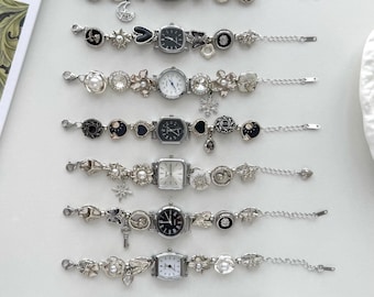 May include: Eight silver-toned charm bracelet watches arranged in a vertical row. Each watch features a unique combination of dangling charms including stars, moons, hearts, flowers, and pearls, attached to a link chain with a lobster clasp closure.