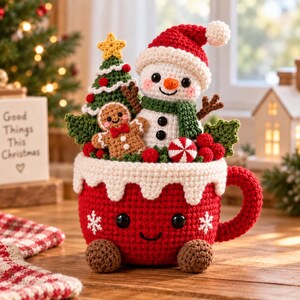 May include: A red crocheted mug with a smiling face and white snowflake accents, filled with a crocheted snowman wearing a red hat, a gingerbread person, a green Christmas tree with a yellow star, red berries, and a peppermint candy.