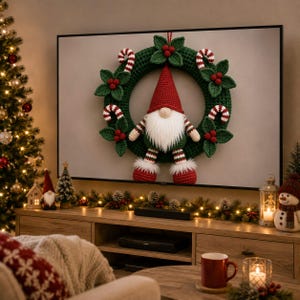 May include: A crochet Christmas wreath featuring a central gnome with a red hat and white beard, surrounded by green leaves, red berries, and red and white candy canes. The wreath is displayed on a television screen in a decorated room.