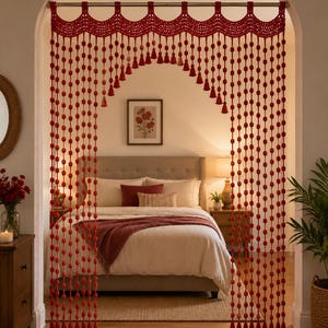 Puede incluir: Una cortina de puerta de ganchillo en color rojo intenso con un borde superior festoneado y hebras verticales de pequeñas cuentas esféricas y borlas. La cortina cuelga de una barra de metal y enmarca una entrada arqueada a un dormitorio.