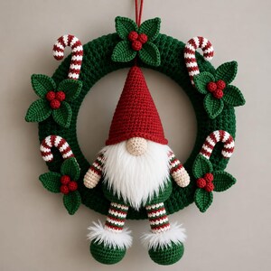 May include: A crocheted Christmas wreath featuring a dark green base adorned with red and white candy canes and green holly leaves with red berries. A central gnome figure wears a red pointed hat, has a white beard, and striped legs.