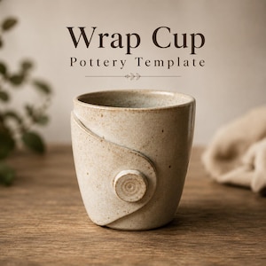 Pu&ograve; includere: Una tazza in ceramica beige maculata con un design avvolgente caratterizzato da un dettaglio circolare simile a un bottone sul davanti. Il testo "Wrap Cup Pottery Template" &egrave; stampato in lettere marrone scuro sopra la tazza, con una piccola foglia.