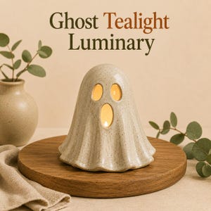 May include: A ceramic ghost tealight luminary with a speckled beige finish. The ghost figure features two oval eye cutouts and a larger oval mouth cutout, allowing warm light to glow from within. The text Ghost Tealight Luminary is visible.