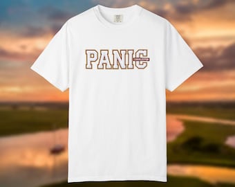 May include: A white short-sleeve t-shirt featuring the word PANIC in large, block-style letters with a dark red outline. The word CHARLESTON is printed in a smaller, rectangular dark red box positioned to the right of the letter C.