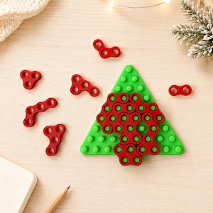 May include: A green triangular pegboard shaped like a tree with a grid of raised circular pegs. Several red interlocking plastic pieces with circular cutouts are arranged on the board, while additional loose red pieces lie scattered nearby.