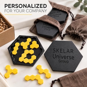 May include: A black hexagonal puzzle board with yellow hexagonal pieces, accompanied by black hexagonal coasters engraved with the text Skelar Universe Group, brown drawstring fabric pouches, and a cardboard box with the text PERSONALIZED FOR YOUR COMPANY.