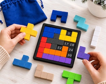 Può includere: Una tavola da puzzle quadrata con cornice nera contenente blocchi a incastro colorati. Alcuni blocchi riportano i numeri 5, 17, 18, 22, 24 e 30. Altri blocchi sciolti di colore giallo, blu, turchese, bianco, viola, beige e verde sono disposti.