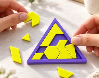 Può includere: Una cornice triangolare viola per puzzle contenente diversi pezzi geometrici gialli, con ulteriori forme gialle sparse nelle vicinanze. Il puzzle presenta vari poligoni tra cui un esagono, parallelogrammi e triangoli.