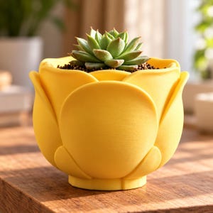 May include: A bright yellow flower-shaped planter with overlapping petal designs. The pot contains a small, green, rosette-shaped succulent plant nestled in dark soil. The exterior of the planter has a smooth, matte finish and a rounded base.