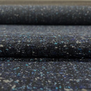 May include: Close-up of a dark blue fabric with a speckled pattern of white and blue flecks. The fabric has a textured, slightly fuzzy surface.
