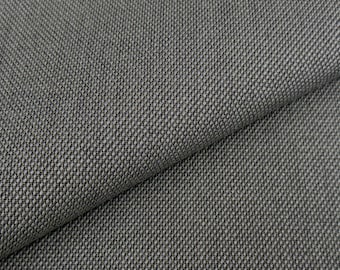 May include: Close-up of a textured, dark gray fabric with a woven pattern. The fabric is folded, revealing the texture and the direction of the weave. The material appears to be durable and suitable for upholstery or clothing.