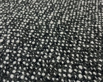 May include: A close-up view of a textile fabric featuring a dense, woven pattern of black and white threads. The material displays a textured, speckled appearance created by the alternating dark and light fibers interlaced throughout the surface.
