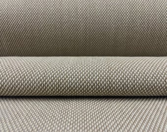 May include: A roll of fabric featuring a tight, woven texture in a neutral beige and off-white color palette. The material displays a consistent, repeating grid-like pattern created by the interlacing of light and dark threads across the surface.