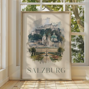 May include: A framed wall art print featuring a watercolour-style illustration of the Salzburg cityscape, including the Hohensalzburg Fortress, historic cathedrals, and the Mirabell Gardens, with the text SALZBURG printed in dark capital letters.