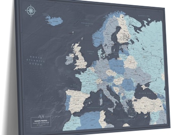 May include: A rectangular wall map of Europe featuring a dark charcoal background with countries highlighted in shades of light blue and cream. A compass rose is in the top left corner, and a label in the bottom left reads EUROPE TRAVELS.
