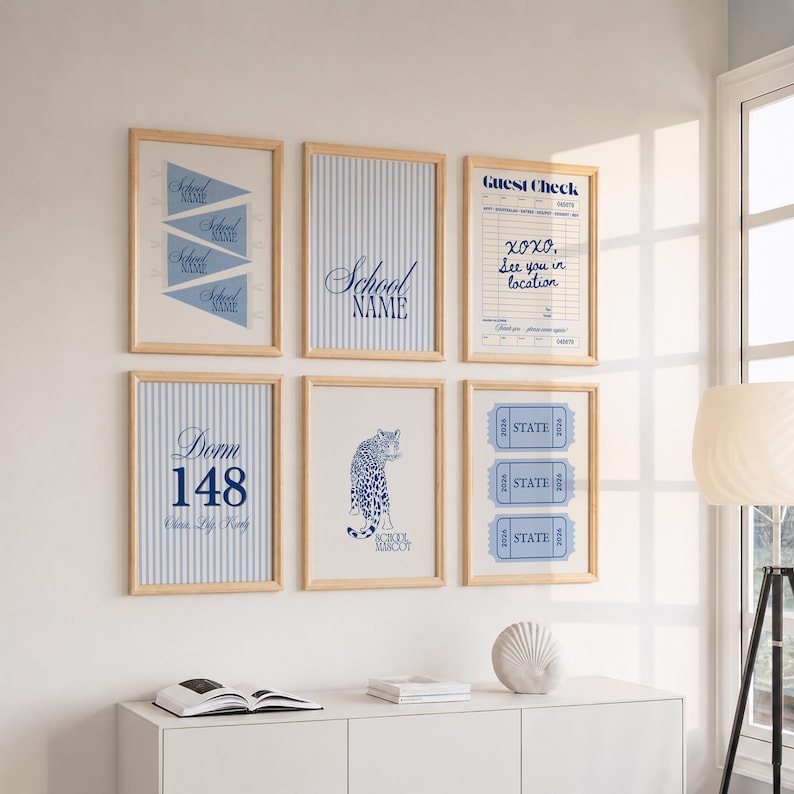 May include: Six framed wall art prints in light wood frames. The prints feature blue and white designs including pennants, vertical stripes, a guest check, the text Dorm 148, a leopard illustration labeled School Mascot, and three state tickets.