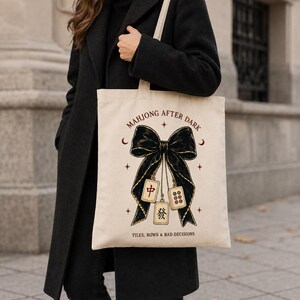 Canvas tote bag featuring a coquette black bow, Mahjong tiles and game night saying.
