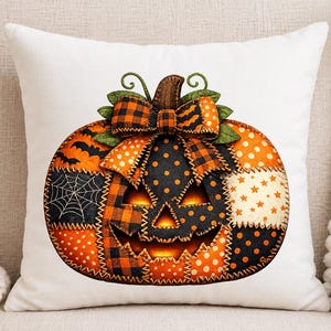 May include: A white square throw pillow featuring a central graphic of a patchwork pumpkin. The pumpkin is composed of orange and black fabric patterns including polka dots, plaid, stars, and spiderwebs, topped with a large plaid bow.