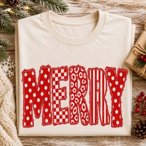 May include: A cream-colored t-shirt featuring the word MERRY in large, red, distressed-edge letters. Each letter displays a different pattern: polka dots, a red and white checkerboard, a leopard print, vertical stripes, and more polka dots.
