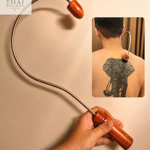 May include: A curved metal massage tool featuring a polished wooden handle and a matching wooden ball at the tip. The device is designed for reaching back muscles, with a long, slender metal shaft that allows for targeted pressure application.
