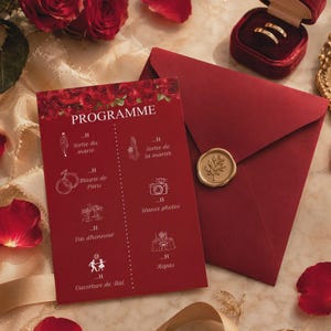 Puede incluir: Una tarjeta de programa de boda en rojo intenso con borde floral, iconos de líneas blancas y texto que incluye "PROGRAMME", "Sortie du marié", "Mairie de Paris" y "Repas". Junto a ella, un sobre rojo a juego con un sello de cera dorado y un joyero.
