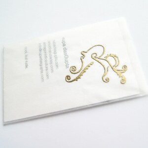 May include: White business card with gold lettering. The text reads "rupa dasGupta" and includes the website address "rupadasgupta.com". A stylized gold octopus design is in the upper right corner.