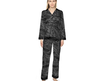 May include: Black pyjama set with a white abstract wave pattern. The top has a collared neckline and long sleeves. The trousers have a straight leg.