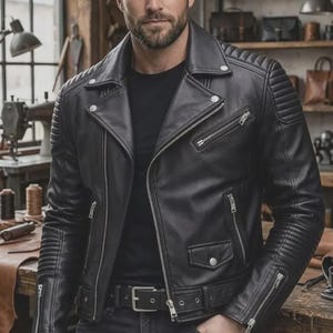 May include: A black leather motorcycle jacket featuring a notched lapel, silver-tone metal zippers, a front belt with a buckle, and quilted shoulder and sleeve detailing. The jacket is worn over a plain black t-shirt and dark denim jeans.