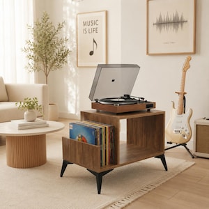 May include: A brown wooden record player stand with black metal legs, featuring an open storage compartment for vinyl records. A turntable with a clear dust cover sits on the top surface of the stand, which is positioned in a room.
