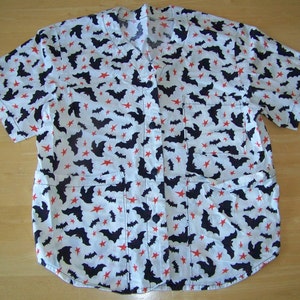 Peut inclure: Une chemise boutonnée à manches courtes blanche avec un motif de chauves-souris noires et d'étoiles rouges.