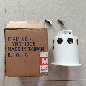 May include: A white cylindrical recessed light fixture housing with circular side cutouts, accompanied by two small metal spring clips. Next to it is a brown cardboard box printed with "ITEM NO.: YMD-1008 MADE IN TAIWAN R. O. C." and a red "M" logo.