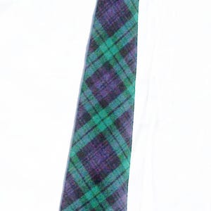 May include: A necktie featuring a plaid pattern in shades of dark purple and bright green. The fabric displays a classic tartan design with intersecting lines of varying thickness, creating a grid-like appearance across the entire length of the tie.