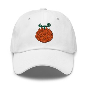 Puede incluir: Una gorra de béisbol blanca con un diseño bordado en el centro de una fruta naranja con patrón de llamas y un tallo verde. La gorra presenta una corona estructurada, una visera curva y ojales para ventilación, con un diseño limpio.
