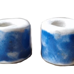 May include: Two ceramic candle holders with a white top and a blue bottom. The blue is a mottled blue with white streaks.